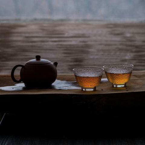 Tea set with a teapot and two cups on a wooden table with a blurred natural background